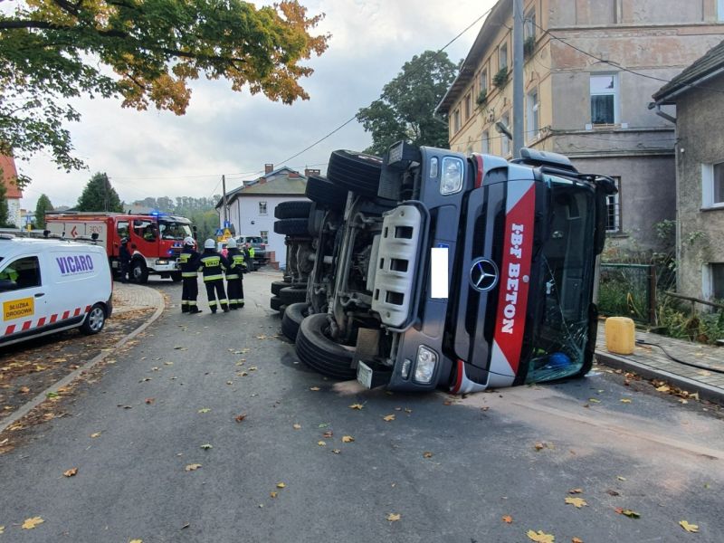 Przewrócona betoniarka i służby mundurowe.